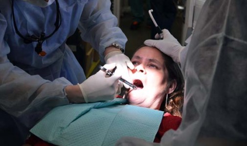 Nohora Hernandez, dental assistant, lightly strokes the head of Vidalia Ruiz, who flinches in tears from the pain of the numbing injections she receives.