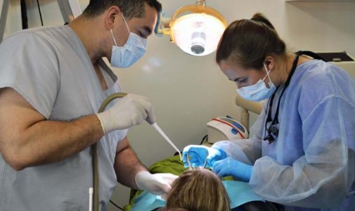 Omar Abarca, dental assistant, and Dr. Rachel Embree, dental resident, examine the site of one woman’s dental pain.